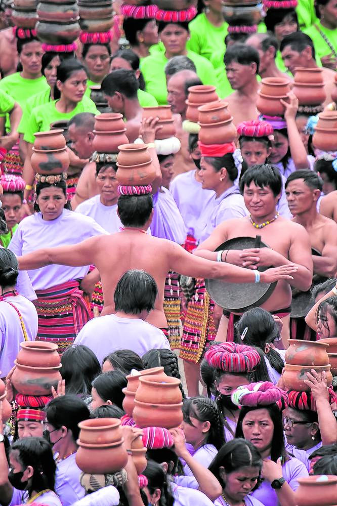 Kalingawomen are entertained by a man balancing a stack of “banga” on his head during a lull in the programwhere the province’s performers smashed the world records for the largest number of gong players and clay pot dancers.