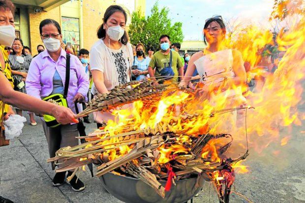 Parishioners of St. John the Evangelist Cathedral in Dagupan City join in the burning of old palms in 2022. The ash will be used in today’s services which begin the Lenten season.  STORY: Catholics to be marked again with ash on forehead