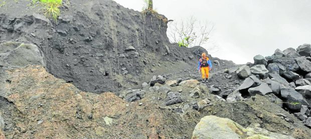 A member of the search and rescue team tasked to find the wreckage of the Cessna plane that crashed on Mt. Mayon on Feb. 18 navigates through a section of the volcano’s slopeon Wednesday, careful not to slip down the sandy area full of jagged volcanic rocks made slippery by days of rain. 