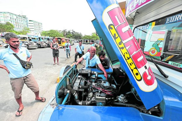 Drivers looking at jeepney with open hood. STORY: Jeepney groups shun talks; strike plan gains backers