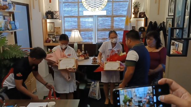 Angyl Faith Ababat and Kristianne Joice Noelle Ona, both second year nursing students at the University of Cebu, receive plaques of appreciation and other gifts from  Cebu City Councilor Rey Gealon on Monday, Feb. 6. (DALE ISRAEL / INQUIRER VISAYAS)