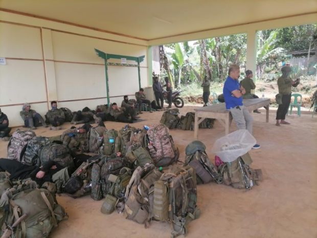 Army soldiers sit idly in front of their backpacks as MILF fighters and members of the Joint Peace and Security Team sit nearby. 