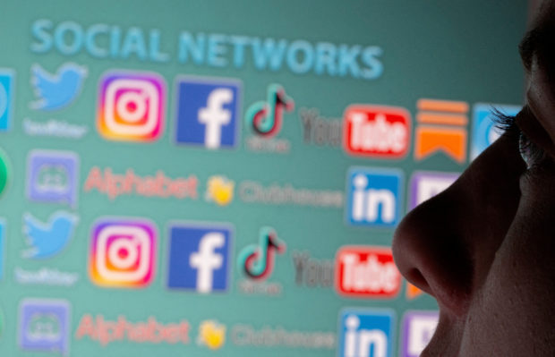 FILE PHOTO: Woman is seen in front of displayed social media logos in this illustration taken