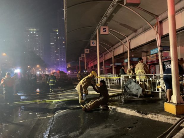 A firefighter comforts a colleague after battling a humungous fire that leveled to the ground a bus station in Cubao, Quezon City. 