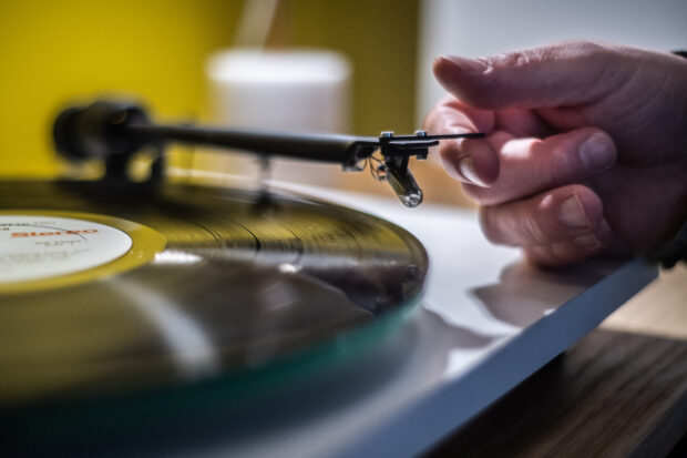 In this file photo taken on February 18, 2020, a man plays a turntable vinyl record player in a music store in Paris. - Sales revenues are "back to their level of 15 years ago, but only 52% of the historical peak of 2002", the organisation said. Sales (i.e. excluding neighbouring rights and synchronisation of films, advertising and video games), at 766 million euros, are "three quarters" based on "digital exploitation". 569 million, including subscription streaming and ad-supported streaming. Physical media, CDs and vinyl, account for the remaining quarter of digital, "exactly the opposite of 10 years ago". (Photo by Martin BUREAU / AFP)