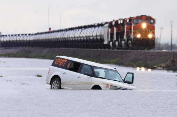 A train passes as floodwaters from the Tule River inundate the area after days of heavy rain in Corcoran, California, U.S., March 22, 2023. REUTERS/David Swanson