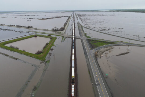 A train passes as floodwaters from the Tule River inundate the area after days of heavy rain in Corcoran, California, U.S., March 22, 2023.  REUTERS/David Swanson