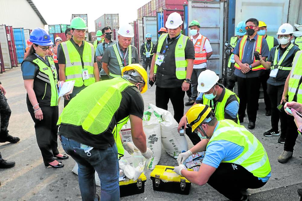 Bureau of Customs employees on Thursday inspect the sacks of refined sugar from Thailand, falsely declared as rubber materials, that arrived at the port of Subic in December last year