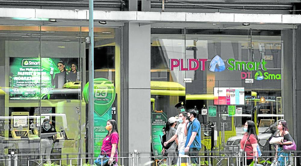 Pedestrians pass by the headquarters of Smart Communications along Ayala Avenue in Makati City.