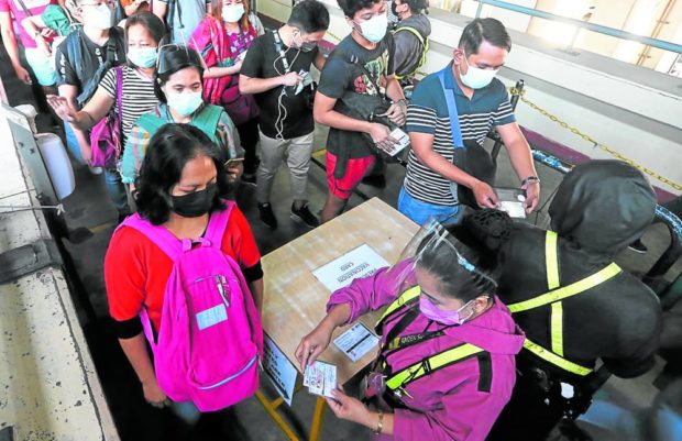 Security guards at MRT 3, in this January 2022 photo, check vaccination and identification cards of passengers at the rail line’s North Avenue Station as the country deals with a surge in COVID-19 cases early last year. STORY: DOT eases face mask, vax proof rule in tourist spots