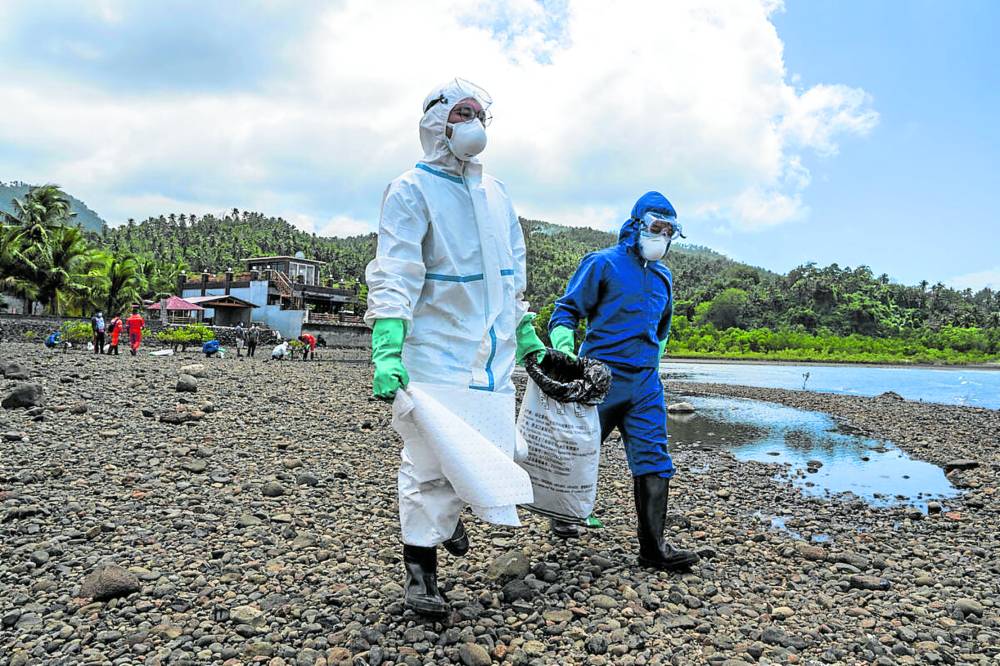 Volunteers in hazmat or protective suits help in the cleanup of the oil spill that continues to affect at least 77 coastal villages in nine towns of Oriental Mindoro province in this photo taken on Thursday.