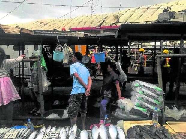 BUSINESS AS USUAL | Fish vendors try to keep it business as usual on Monday, setting up stalls just outside of the section of the Baguio City market that was hit by fire last week. STORY:  Cleanup of debris from fire-hit Baguio market starts