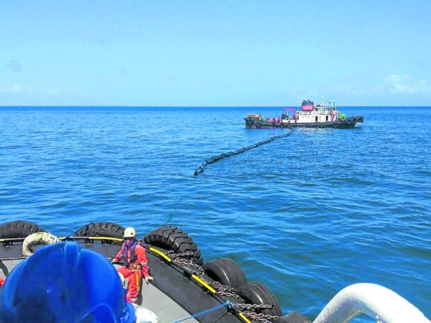 In this photo taken on March 9, Philippine Coast Guard personnel place an oil spill boom in the waters off Naujan, Oriental Mindoro, where a fuel tanker sank on Feb. 28. The operation is part of containment and recovery efforts to prevent oil slick from reaching a wider area in the coastlines of at least three provinces. STORY: Gov’t failures bared in Mindoro oil spill