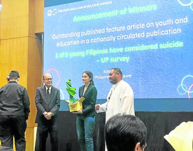 Inquirer reporter and scholar Abby Boiser receives a Toym Imao sculpture as trophy from De La Salle University senior vice president Ramon Trajano (left) and National Brother adviser Richie Yap at the 18th Lasallian Scholarum Awards STORY: Inquirer story wins La Salle Scholarum media award
