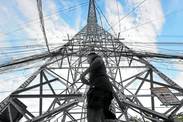 TRANSMISSION TOWER A pedestrian walks past a transmission tower of the National Grid Corp. of the Philippines (NGCP). The NGCP warns of power interruptions during summer without the needed ancillary services. —inquirer file photo