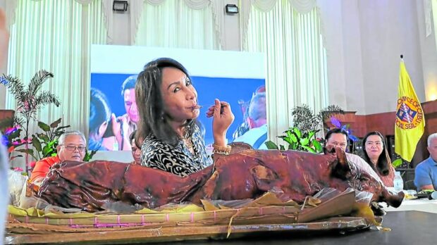 Gov. Gwendolyn Garcia, during a meeting with local officials on March 21, eats “lechon,” one of Cebu’s best-selling food products, to prove that local pork is safe for consumption despite the detection of African swine fever cases in the province
