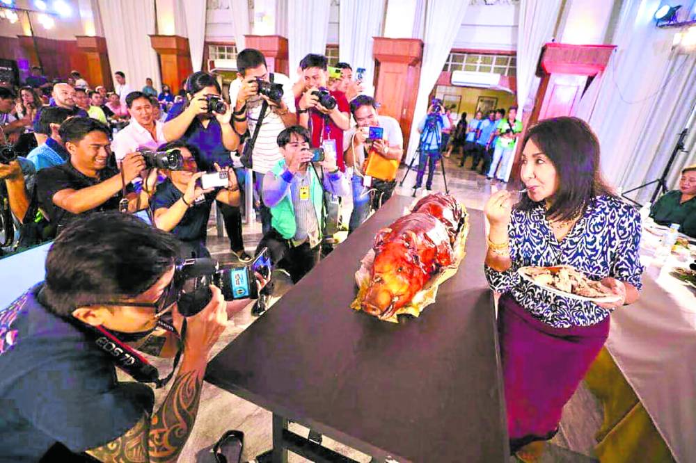 Cebu Gov. Gwendolyn Garcia posesfor photographers at the Capitol Social Hall on March 21 as she tastes the famous “lechon” of Carcar City to show that roasted pigs and other pork products from Cebu are safe to eat despite the report of the Bureau of Animal Industry that African swine fever has infected Cebu’s hog farms.