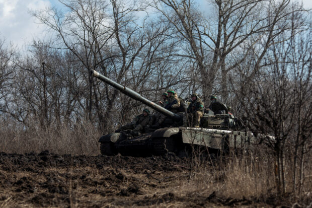 FILE PHOTO: Ukrainian service members ride atop of a tank outside of the frontline town of Bakhmut