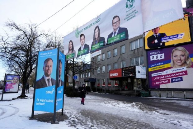 A person walks past Estonian political parties general election campaign placards next to the shopping mall in Tallinn, Estonia March 1, 2023