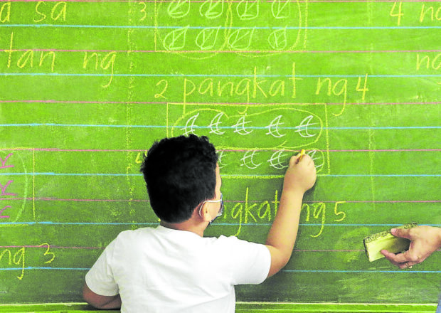 A students writing on a blackboard. STORY: Grades 1-12 private school learners flunk math, science assessment