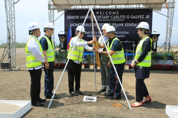 Defense chief Carlito Galvez Jr. assisted by the Philippine Air Force acting commanding general Ramon Guiang fills the time capsule with documents during the groundbreaking ceremony at Basa Air Base on Monday. 