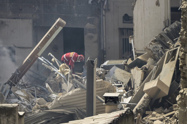 A firefighter looks into the rubble at 'rue Tivoli' after a building collapsed in the street, in Marseille, southern France, on April 9, 2023. - "We have to be prepared to have victims," the mayor of Marseille warned on April 9, 2023 after a four-storey apartment building collapsed in the centre of France's second city, injuring five people, according to a provisional report. (Photo by CLEMENT MAHOUDEAU / AFP)