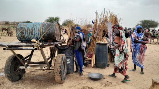 A Sudanese woman, who fled the violence in her country, tries to get water from a barrel near the border between Sudan and Chad in Adre, Chad  April 26, 2023. REUTERS/Mahamet Ramdane