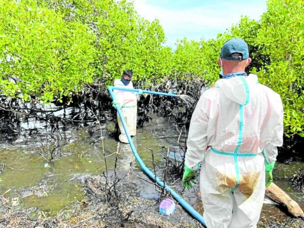 Personnel from Philippine Coast Guard (PCG) seen using low-pressure pumps to flush out remaining oil sludge in mangrove areas in the coastal village of Tinogboc, Semirara Island in Caluya, Antique.
