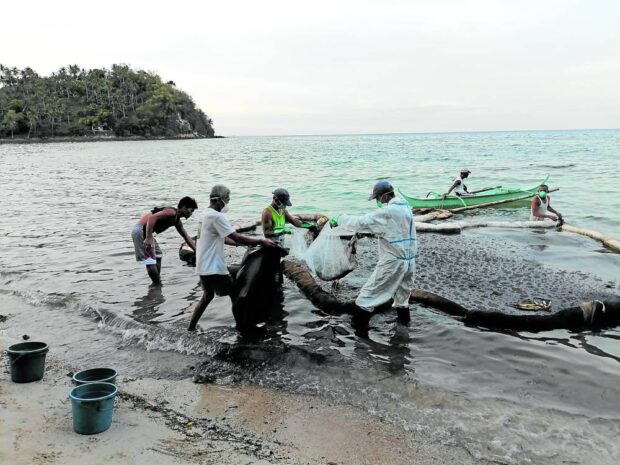 Villagers in Calapan City, Oriental Mindoro, collect the oil sludge from sunken MT Princess Empress using booms made of coconut husks, fishnets and jute sacks to protect their coastal resources in this photo taken on April 1. The spill continues to take its toll on the livelihood of local fishers.