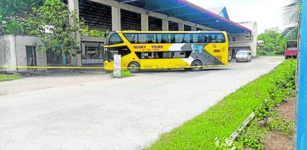 This double-deck bus owned by Husky Tours is cordoned with a yellow police line and guarded by a patrol car at an emptied section of the bus terminal in Isulan, Sultan Kudarat province, after a bomb exploded inside the vehicle while it was parked at the terminal at noon on Monday, injuring six persons. STORY: Sultan Kudarat police on alert after bus bombing in capital town