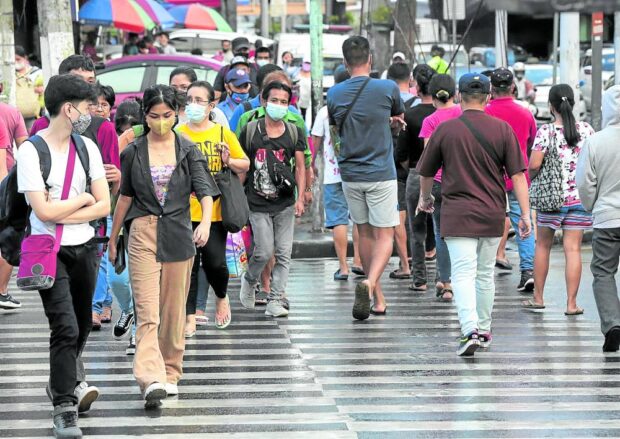 VIRUS STILL HERE Pedestrians, many of them wearing face masks, cross Kamuning Road in Quezon City in this photo taken in September 2022. Metro Manila has seen an increase in COVID-19 cases, with its positivity rate breaching the 5-percent threshold set by the World Health Organization. —GRIG C. MONTEGRANDE alert level system covid-19