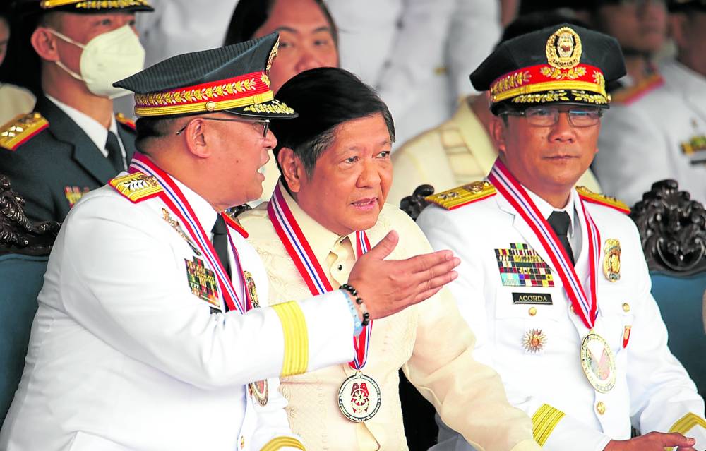 LEADERSHIP CHANGE President Marcos talks to outgoing Philippine National Police chief Gen. Rodolfo Azurin Jr. (left) during the turnover of command to Maj. Gen. Benjamin Acorda Jr. (right) at Camp Crame on Monday. —NIÑO JESUS ORBETA term extend