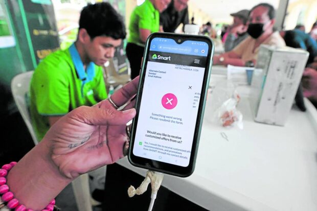 LAST-MINUTE QUEUE Mobile phone users queue to register their SIM at a telecommunication company’s booth set up at Quezon City Hall on Tuesday, a day before the original deadline set by the government. —GRIG C. MONTEGRANDE 