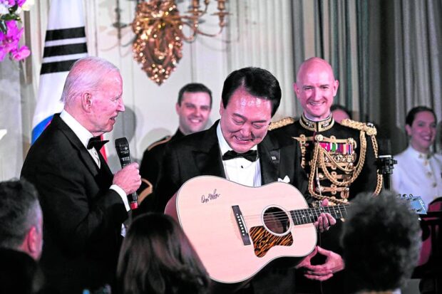 US President Joe Biden (L) hands South Korean President Yoon Suk Yeol a guitar signed by US singer Don McLean as a gift during a State Dinner with US President Joe Biden at the White House in Washington, DC, on April 26, 2023. south korean american pie