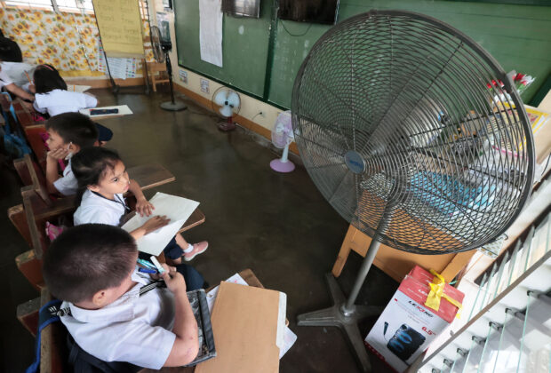 FANS OF ALL SIZES Grade 1 pupils at Pinyahan Elementary School in Quezon City finish their seatwork on Monday without worrying too much about the summer heat as their classroom is cooled down by several electric fans in the absence of expensive air-conditioning units. —GRIG C. MONTEGRANDE