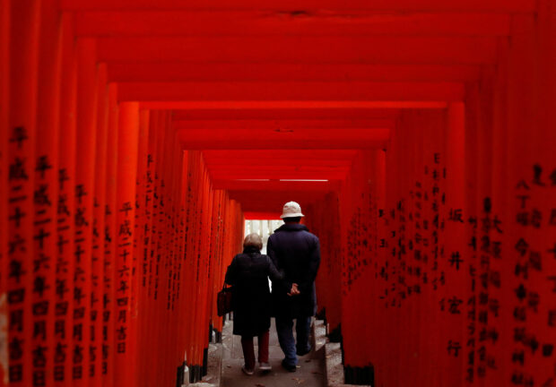 n elderly couple walks through red-coloured wooden torii gates at a shrine, amid the coronavirus disease (COVID-19) outbreak, in Tokyo