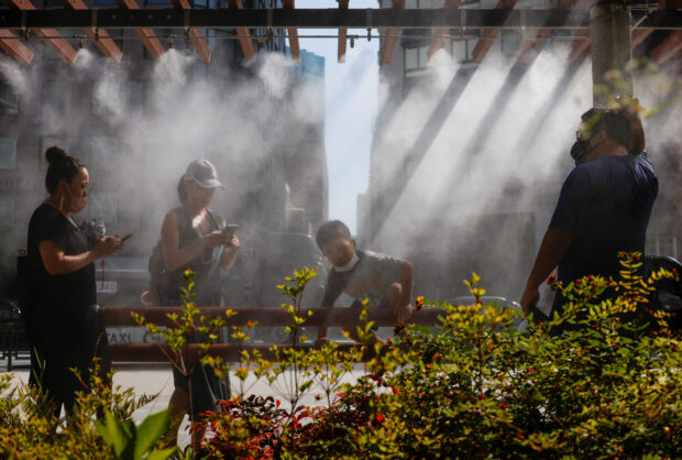FILE PHOTO: People take a break under a cooling mist, in Tokyo