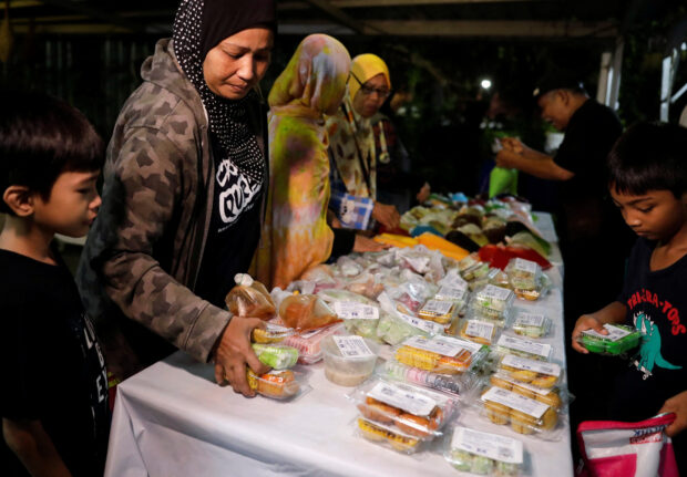 People take unsold food rescued from the bazaar to reduce food waste during the holy month of Ramadan in Kuala Lumpur