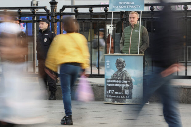 FILE PHOTO: A campaign member stands at a desk promoting Russian army service in Moscow