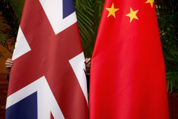 FILE PHOTO: A worker adjusts British and China national flags on display for a signing ceremony at the seventh UK-China Economic and Financial Dialogue "Roundtable on Public-Private Partnerships" in Beijing