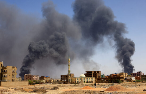 A man walks while smoke rises above buildings after aerial bombardment, during clashes between the paramilitary Rapid Support Forces and the army in Khartoum North, Sudan, May 1, 2023. REUTERS/Mohamed Nureldin Abdallah