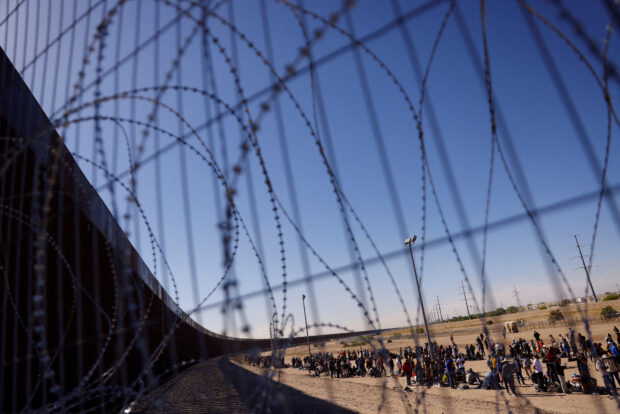 Migrants stand near the border wall after having crossed the U.S.-Mexico border to turn themselves in to U.S. Border Patrol agents, as the U.S. prepares to lift COVID-19 era Title 42 restrictions that have blocked migrants at the border from seeking asylum since 2020, in El Paso, Texas, U.S., May 10, 2023. REUTERS/Jose Luis Gonzalez