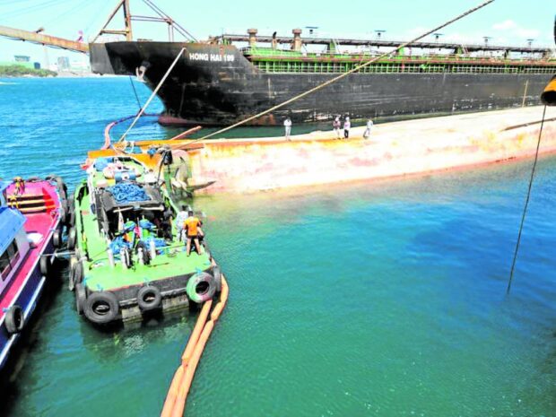 Personnel of the Philippine Coast Guard(PCG) Station in Bataan place oil booms and absorbent bags in the waters around the sunken MV Hong Hai 189 dredger in this photo taken on Monday. 