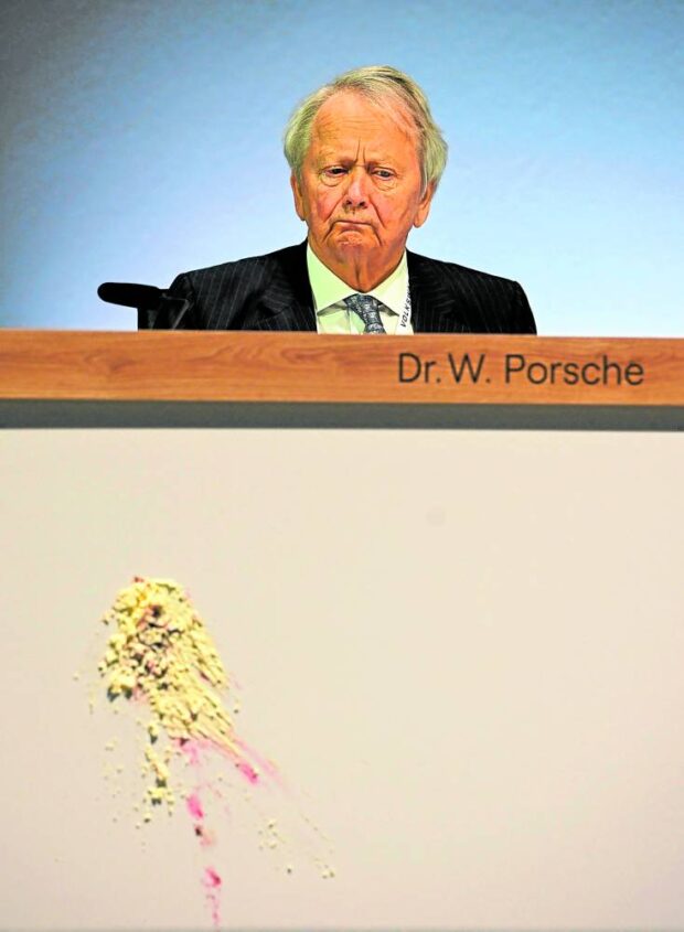 Wolfgang Porsche, board member of German car giant Volkswagen, looks on after a piece of cake has been thrown at the front of his desk during the company’s annual general meeting on May 10 in Berlin.