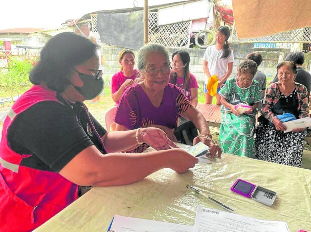 Social workers hand cash aid to survivors of wartime sexual abuses in Candaba, Pampanga, on Friday.