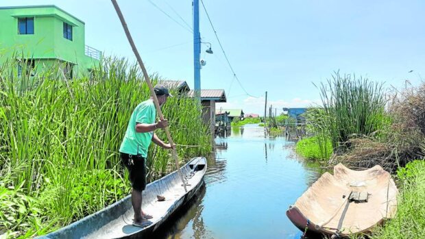 BOAT RIDE Randy Cabildo, a councilman of Barangay San Miguel in Calumpit, Bulacan, rides his small boat to visit a resident in the sunken sitio of Malindig, in this photo taken on May 7. —CARMELA REYES-ESTROPE