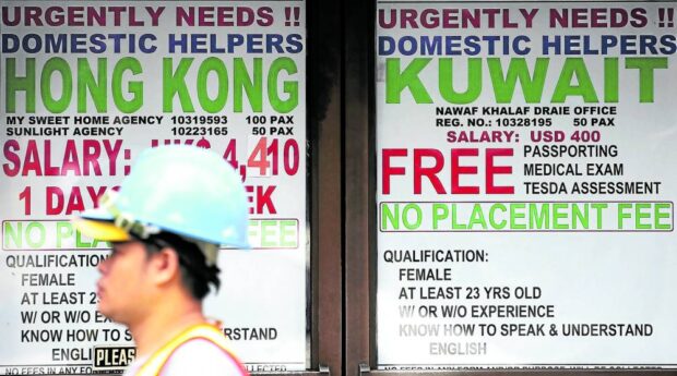 In this photo taken in 2018, advertisements for job openings in Kuwait and Hong Kong are posted by placement agencies in Manila for Filipinos seeking employment abroad. STORY: Long-term solution needed for abuses vs OFWs – Migrante