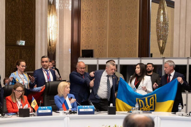 Members of Ukrainian delegation unfurl their national flag next to Olga Timofeeva, deputy head of Russian delegation, to disrupt her speech during a meeting of the Parliamentary Assembly of the Black Sea Economic Cooperation (PABSEC) in Ankara, Turkey May 4, 2023.