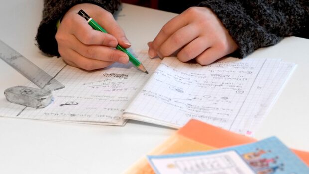Student with pencil and notebook, closeup of hands. STORY: Bill aims to give students ‘no homework’ weekends