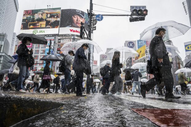 People use their umbrellas to shelter from the rain as they walk through Shibuya district in Tokyo on June 2, 2023. (Photo by Yuichi YAMAZAKI / AFP)